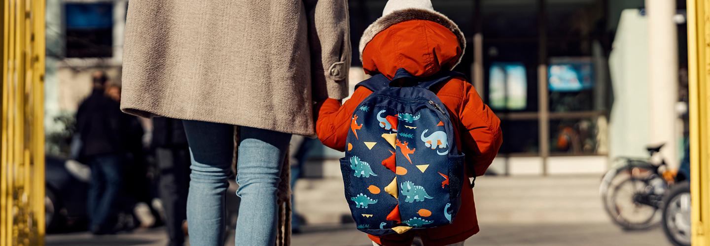 A mother entering the kindergarten yard with her son