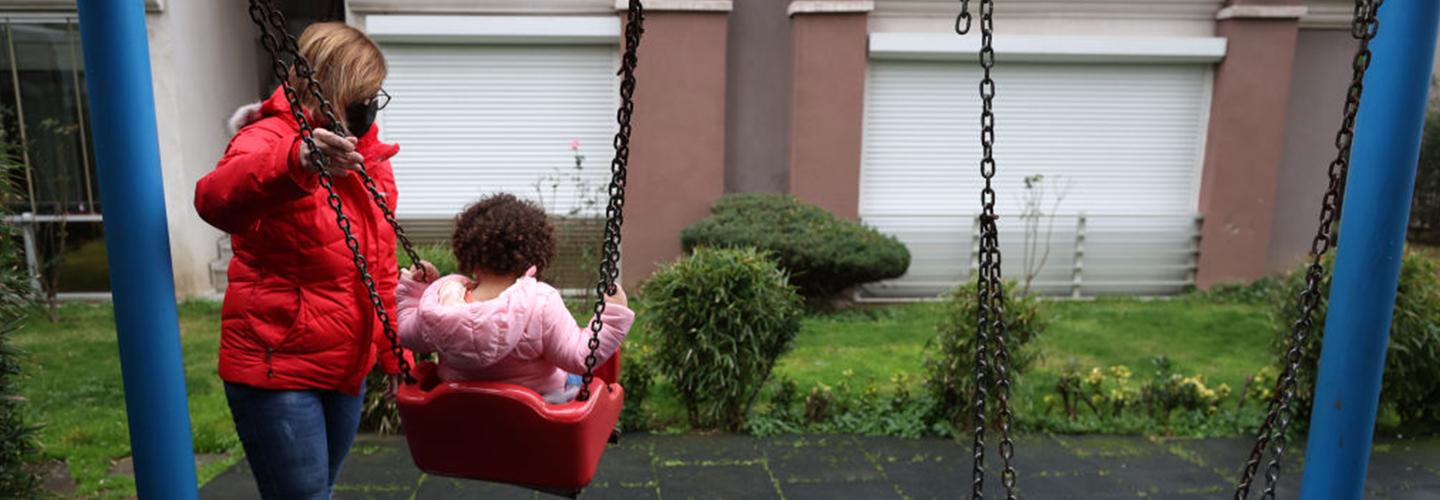 a young girl plays at the park with her mother