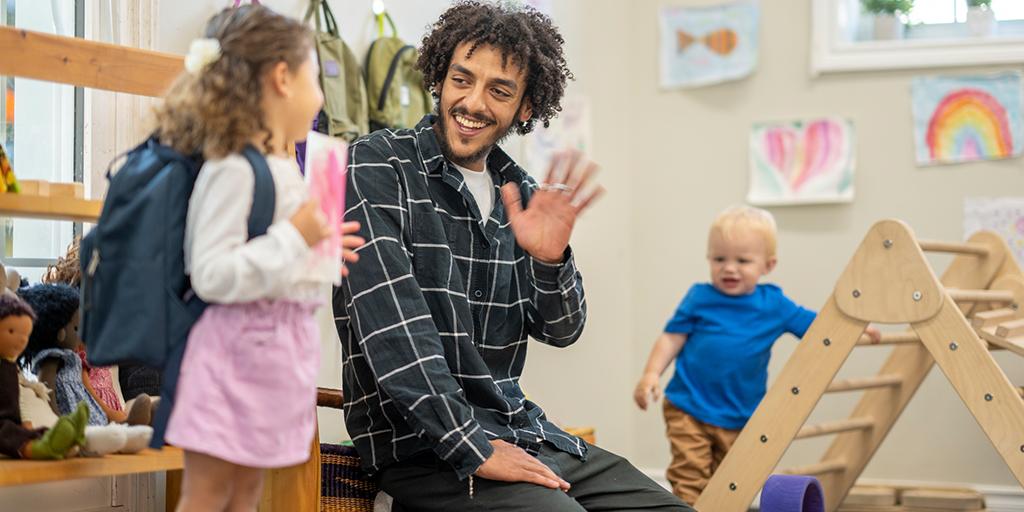 a young child waves goodbye to her daycare teacher