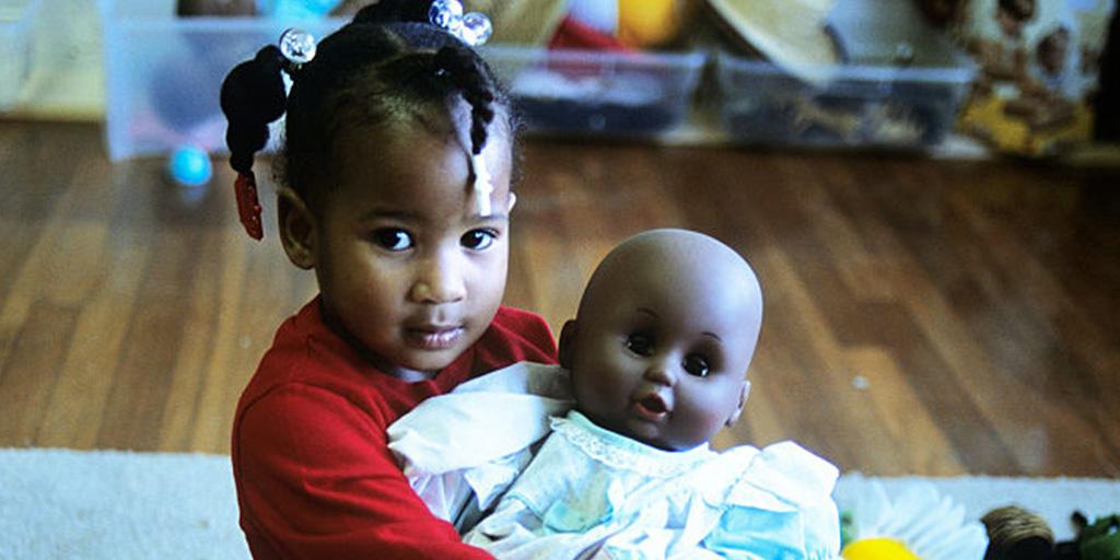 A young girl holds a baby doll