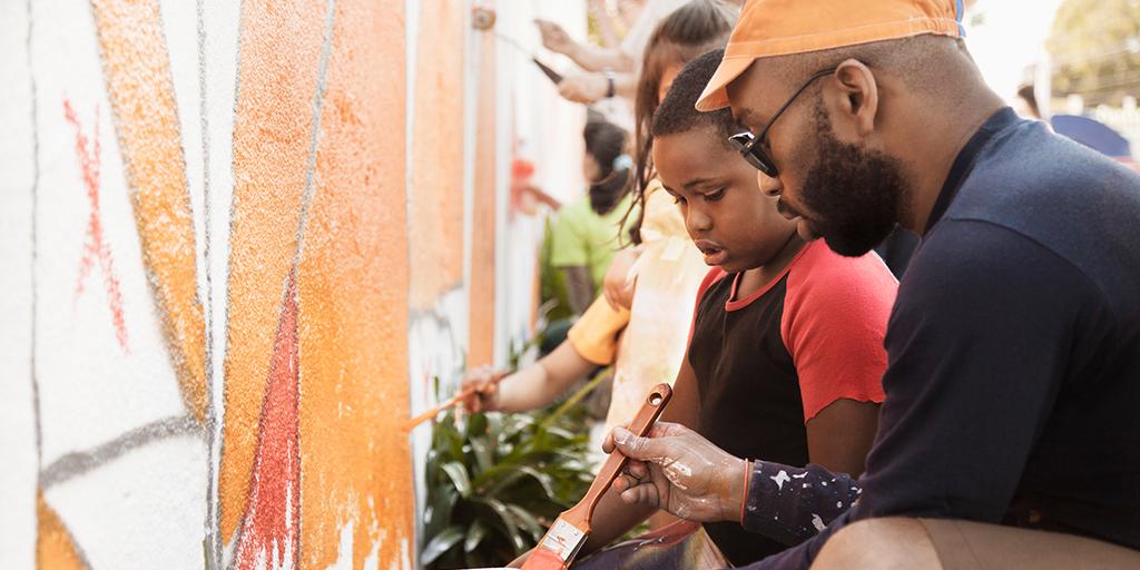 a father and son help paint a mural