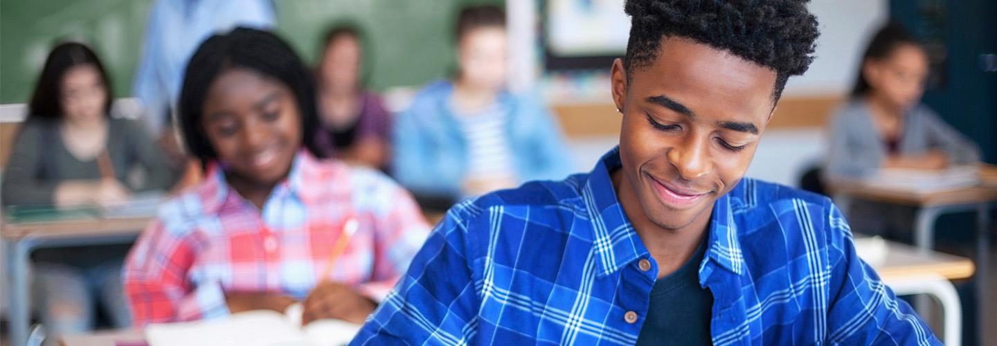 a young man works in a notebook in class