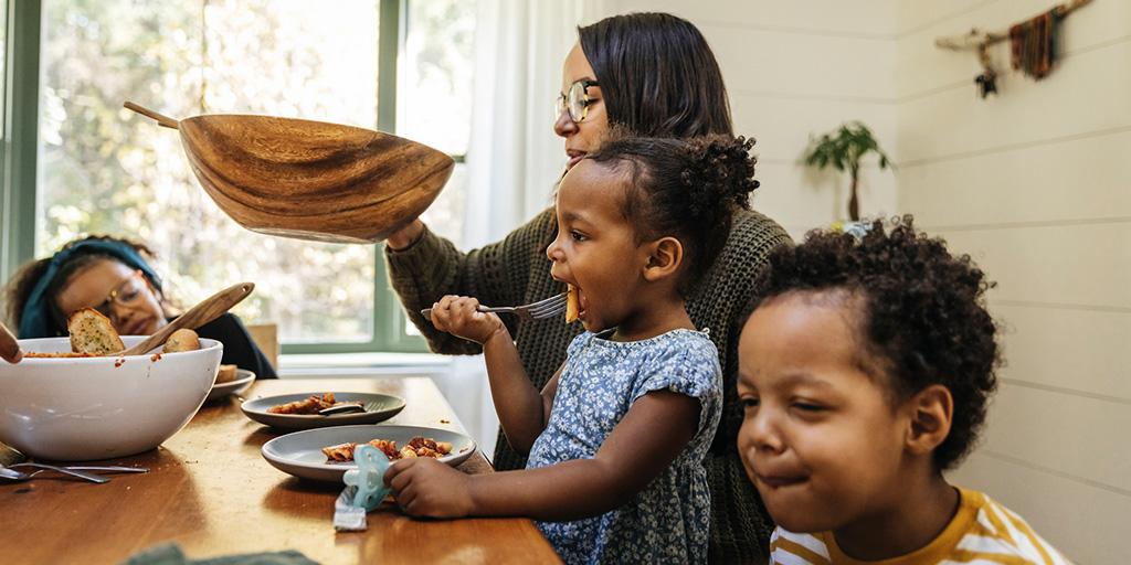 a mother passes the salad bowl at dinner