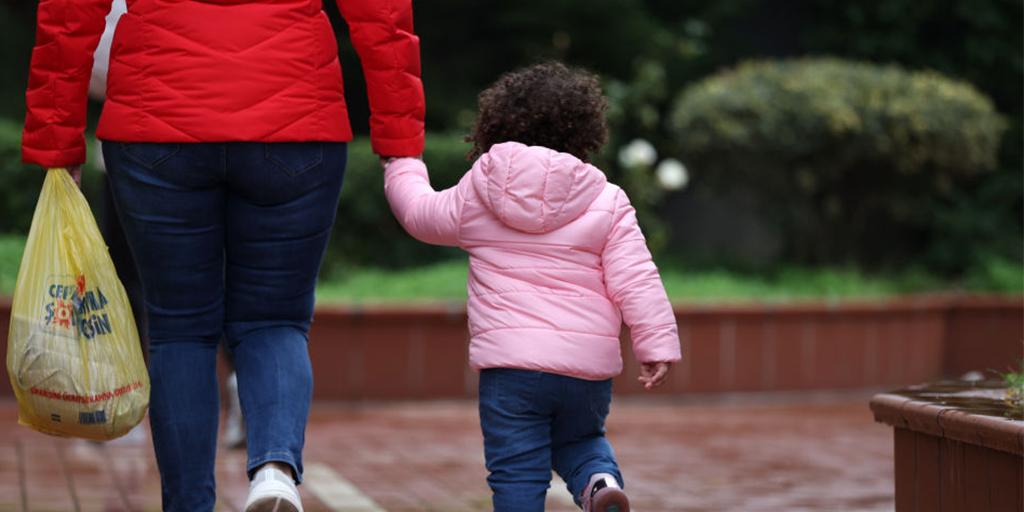 a child walks, holding her mom's hand