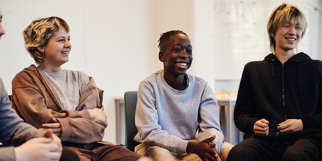 Happy teenage boys and girl sitting together in group therapy