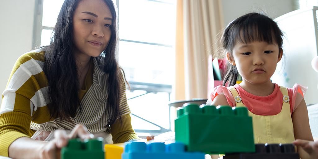 a young girl and her mom play with blocks