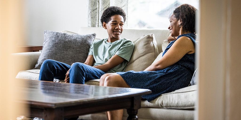 a mother and her teen son sit on a couch