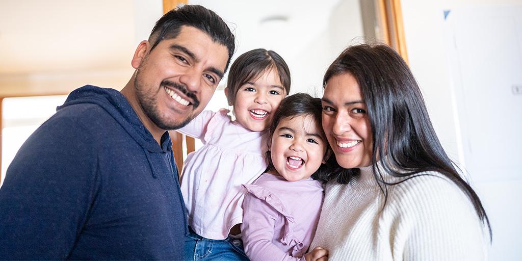 a family of four smiles at the camera